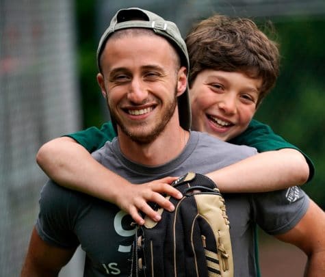 camp counselor giving a camper a piggy back ride