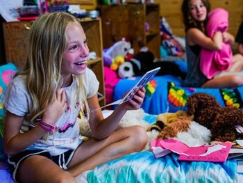 young girl on bed reading a letter and laughing