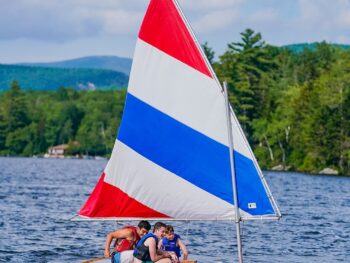 three boys sitting on a sailboat