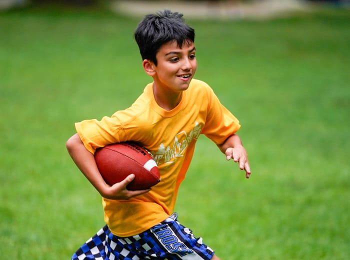 young boy running with a football