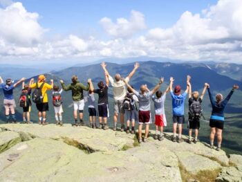 group of boys on the edge of a cliff rock with their hands up