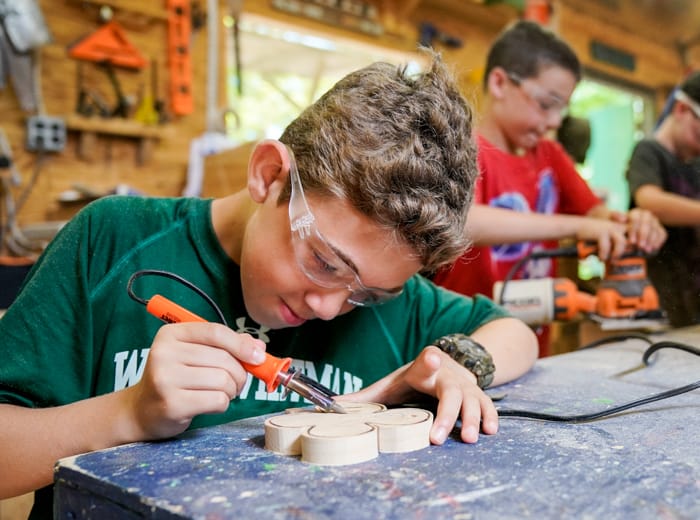 young boy soldering a four leaf clover in woodworking