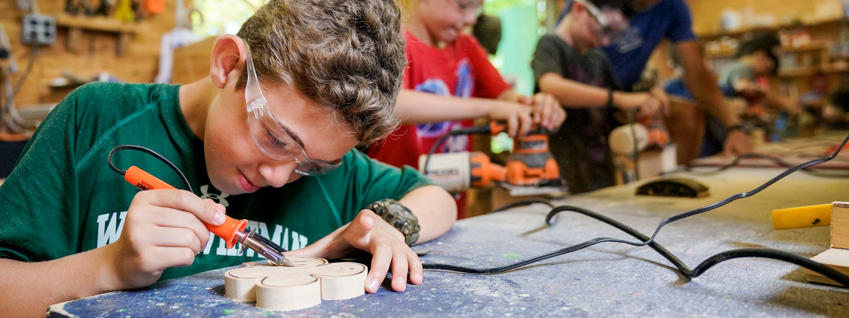 young boy with a soldering iron creating a four leaf clover design