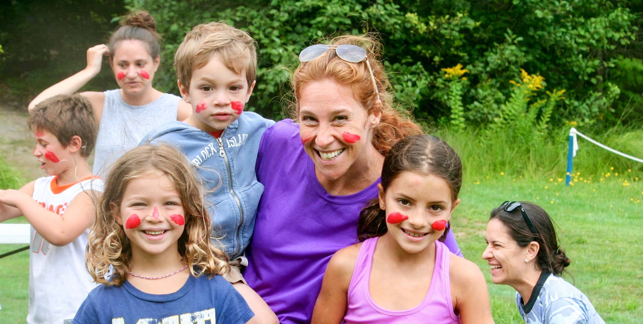 young campers and a red-headed woman with red paint on their faces