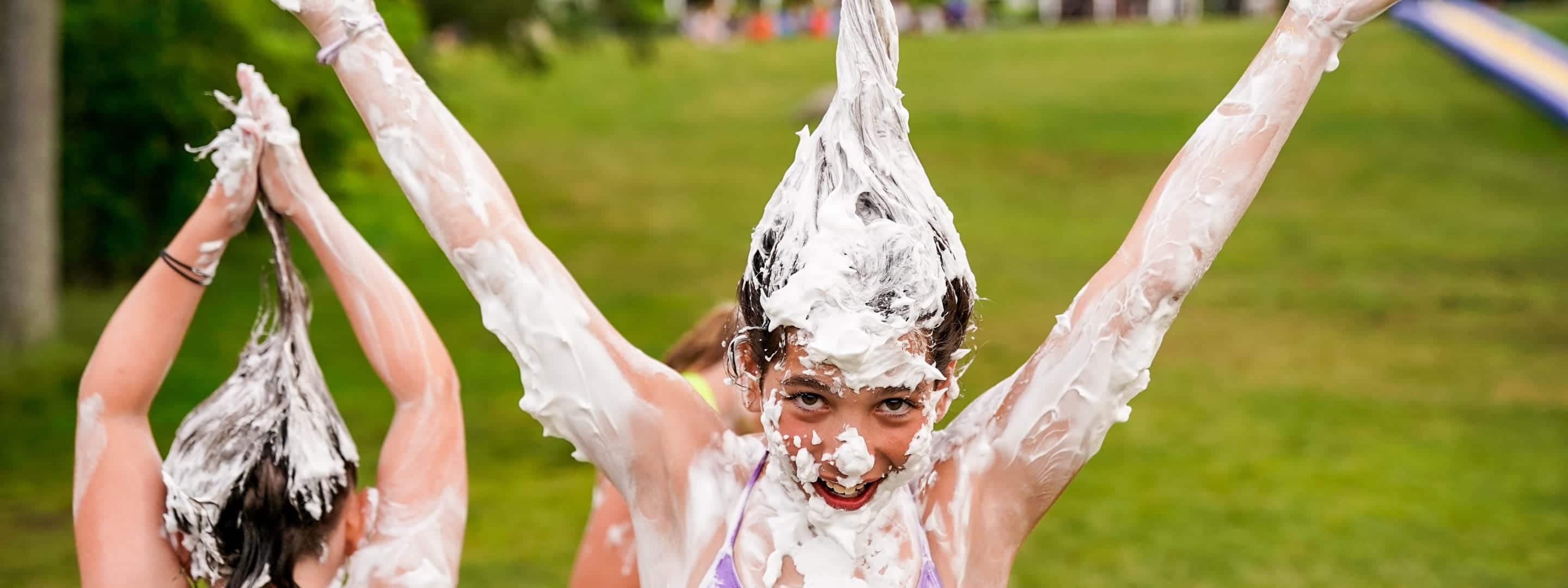 young camper with shaving cream on her and in her hair making it stick straight up