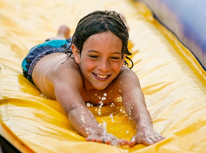 boy smiling while diving on slip and slide