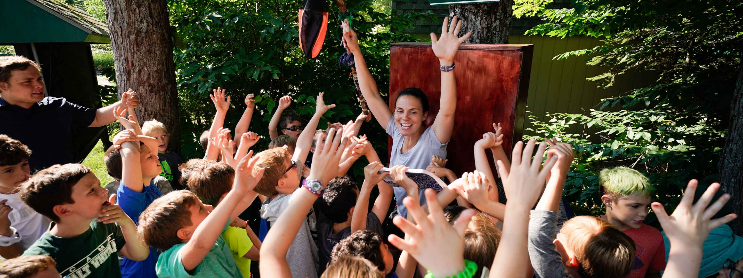 a counselor raising her hands while campers are around her with raised hands