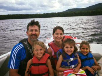 family of 5 smiling on a boat on a lake