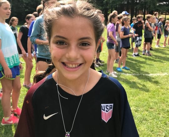 girl smiling with a bunch of kids behind her