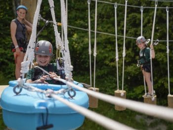 three girls having fun on an aerial ropes course