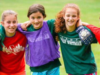 Five children stand in a row with arms around each other, smiling.