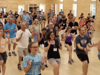 a group of counselors and campers dancing and clapping together