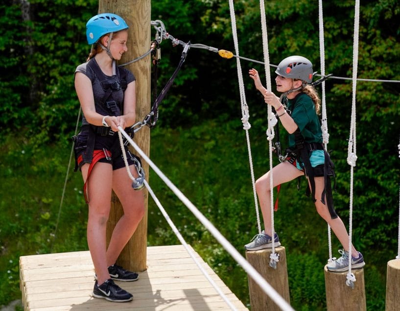 two girls climbing on a ropes course
