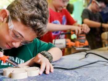 young boy carving a four leaf clover with a woodworking soldering iron