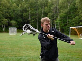 counselor playing lacrosse outside